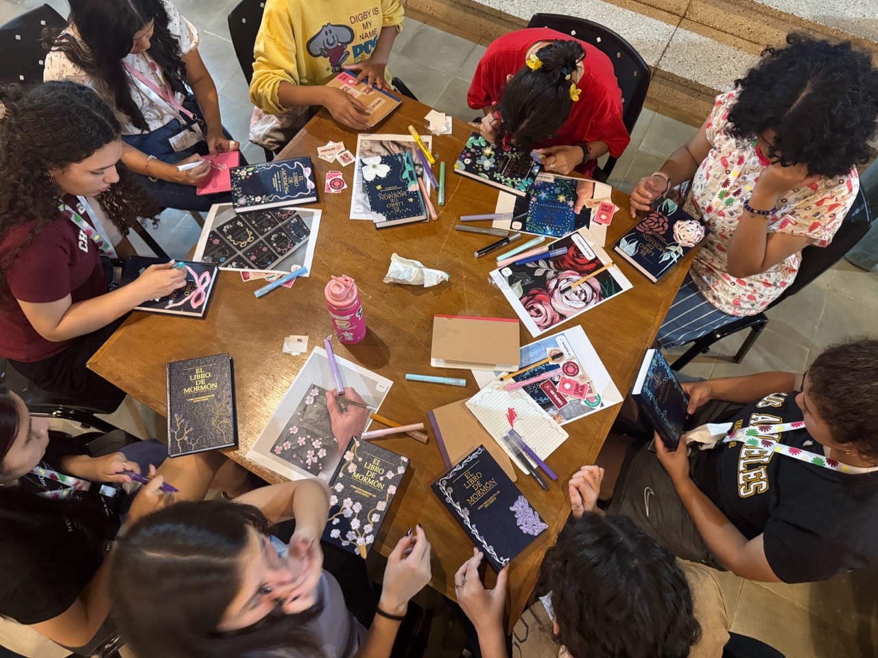 Participantes decorando ejemplares del Libro de Mormón en el retiro Campalma